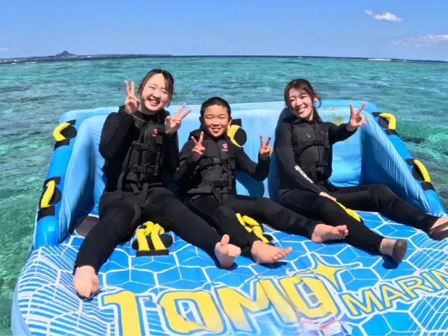水納島で青いチューブに乗り、ピースする3人