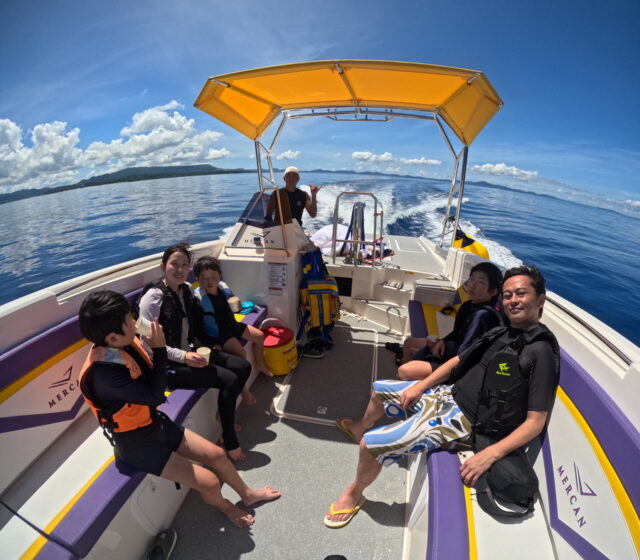 水納島の海を走るボートのデッキでくつろぐ家族