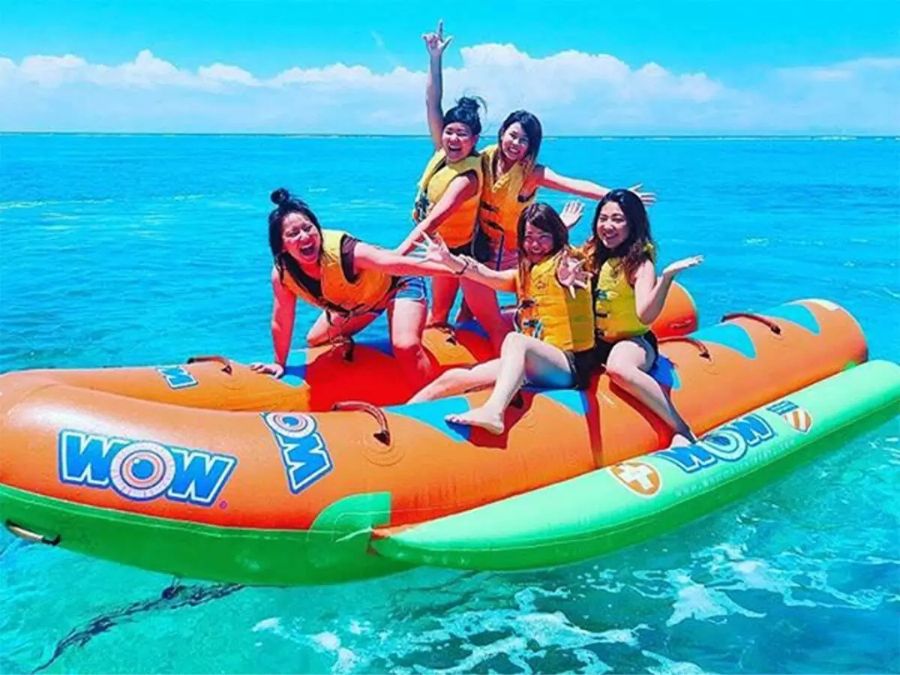 水納島でマリンスポーツを満喫。笑顔でバナナボートに乗る観光客